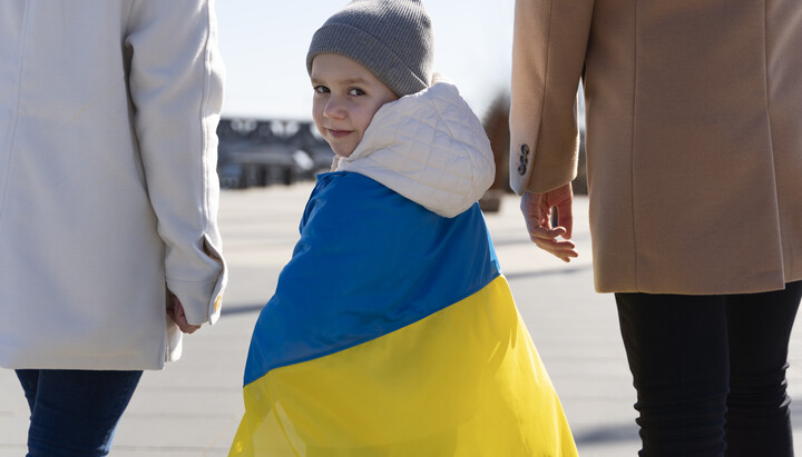 Українська дитина з національним прапором під час акції підтримки біженців у Європі. Фото: obozrevatel